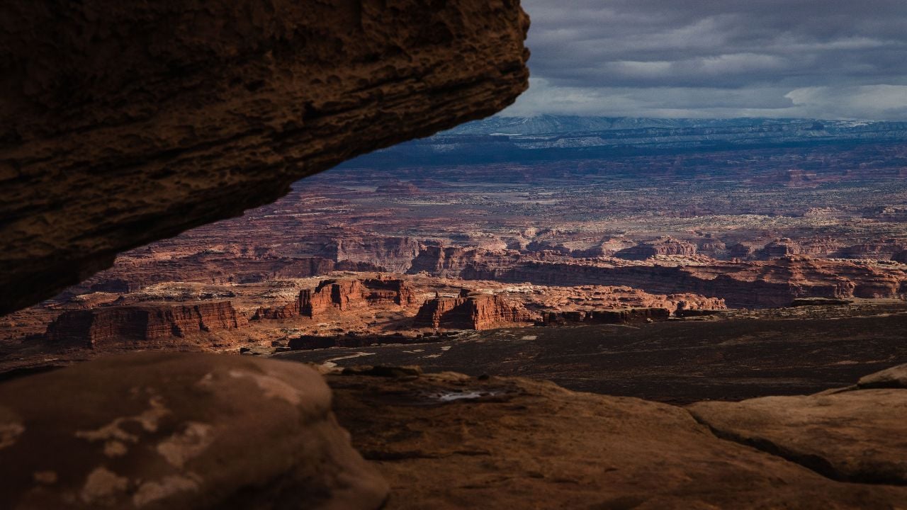 A stunning view of Canyonlands National Park with dramatic rock formations under a cloudy sky, showcasing the rugged beauty of the landscape.