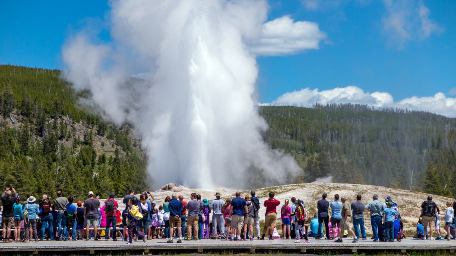 Tourists watching Old Faithful erupt in Yellowstone National Park, Wyoming