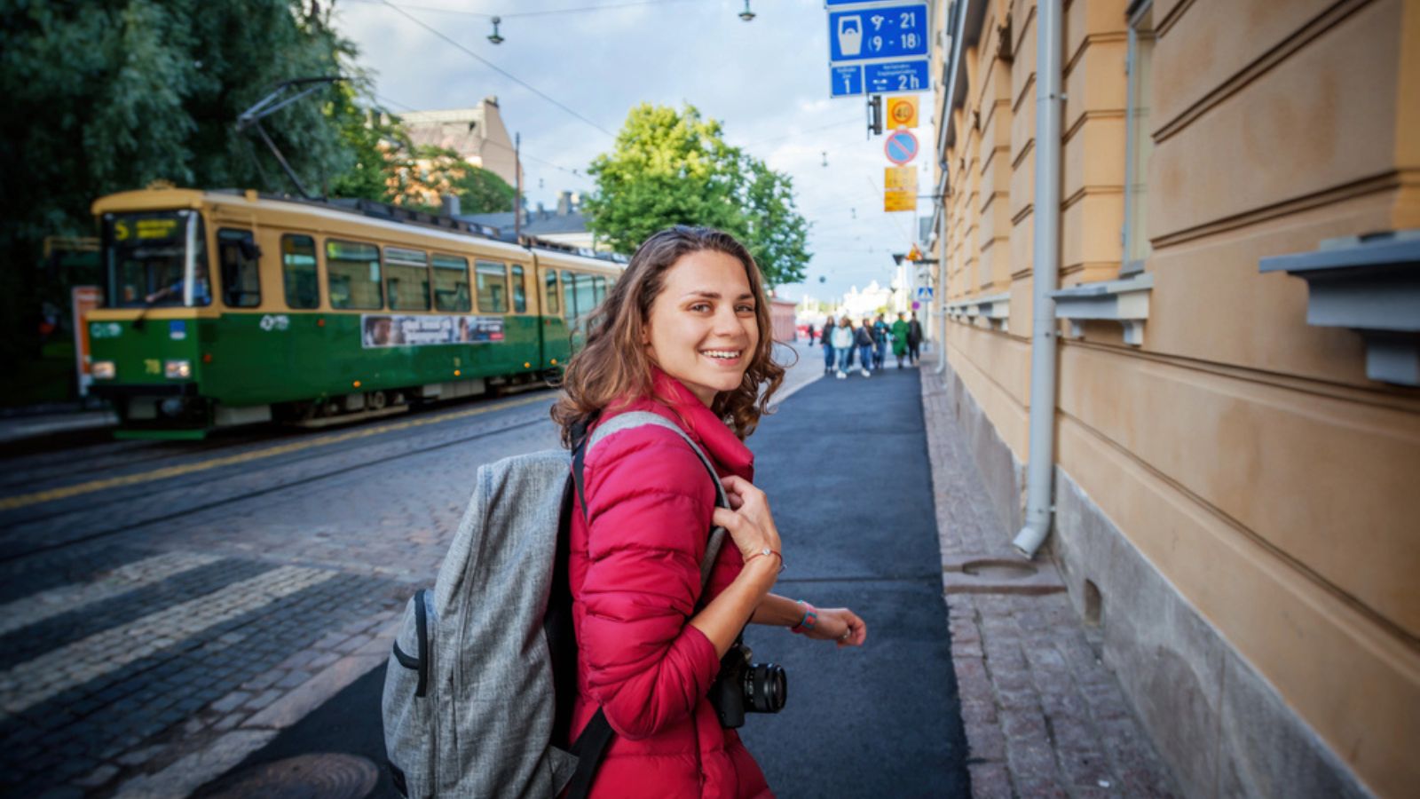 Beautiful-happy-young-woman-girl-tourist-hiker-walks-the-streets-in-Helsinki-Finland-travel-to-Northern-Europe-with-backpack-and-camera (1)