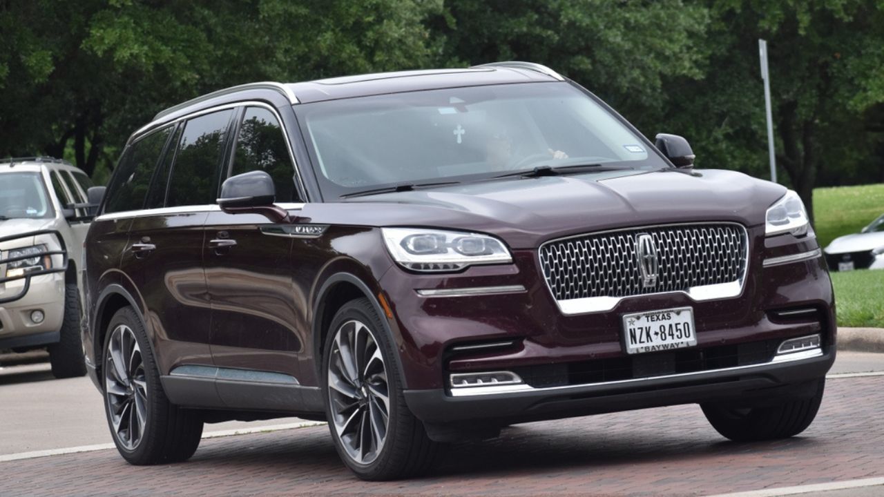 Houston, TX USA - A portrait of a maroon-colored Lincoln Nautilus luxury SUV cruising at a nature reserve.