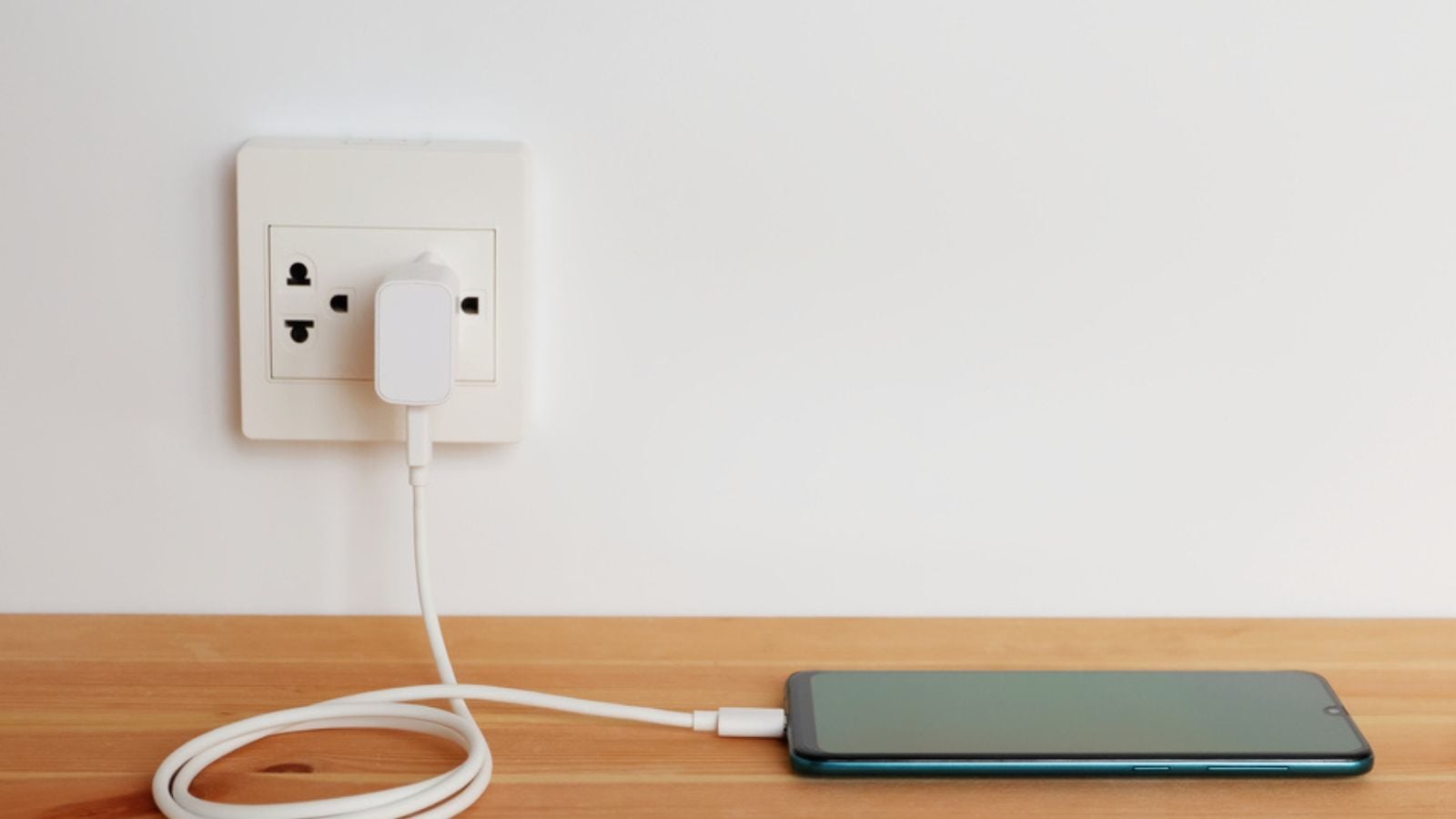 Phone charger plugged into a power outlet with an adapter.