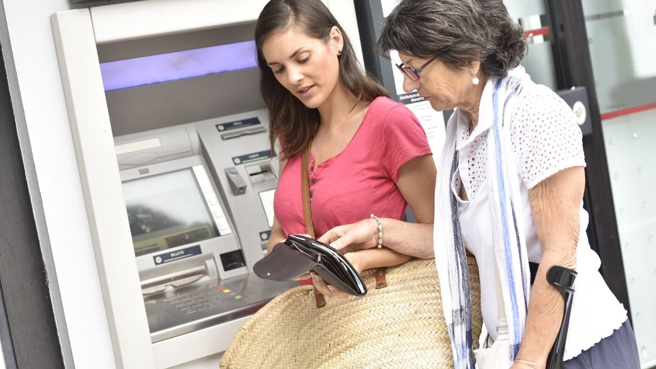 Home carer and disabled woman getting cash from bank