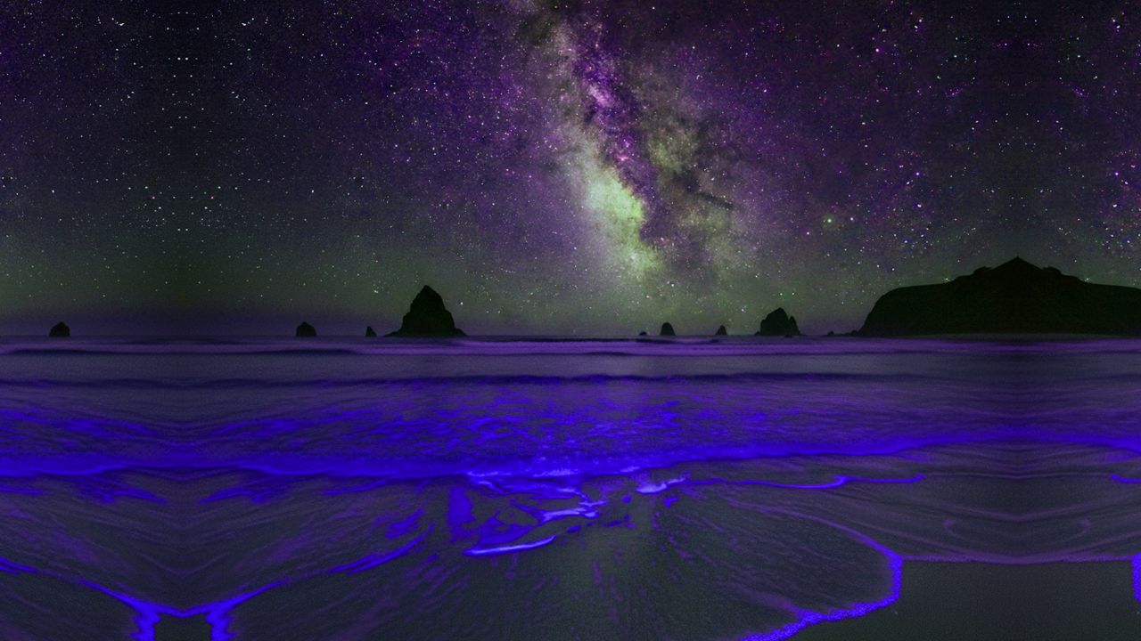 Stunning bioluminescent ocean waves under the Milky Way galaxy. Night sky beach landscape for trendy nature, travel, and celestial designs.