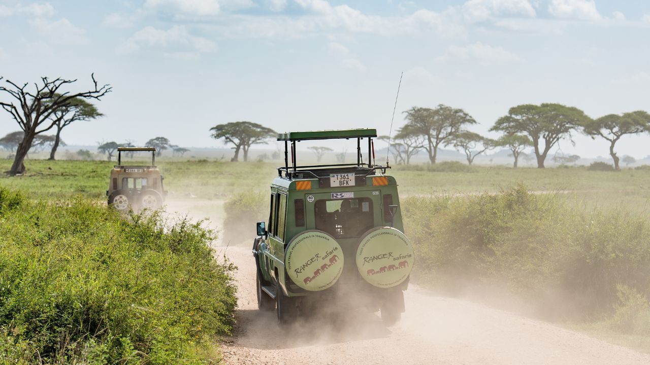 Serengeti National Park / Tanzania - 15 December 2017: Off-road vehicles moving along dusty road in savannah