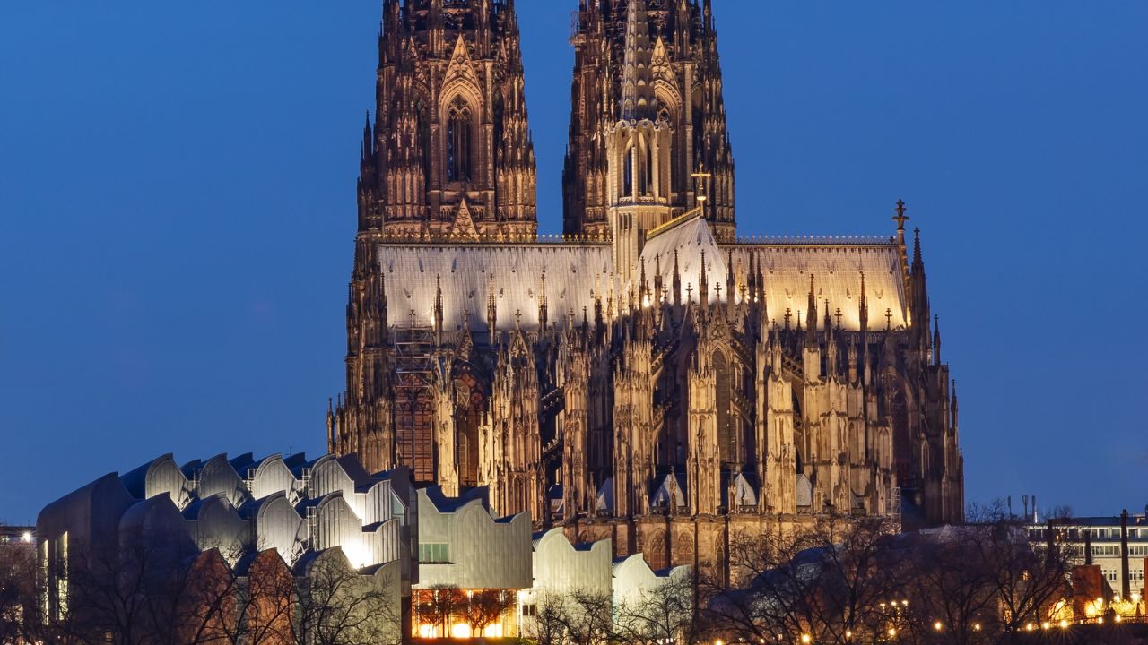 Cologne Cathedral (Kölner Dom) at night with reflections in the river Rhine. The Cologne Cathedral is Germany's most visited landmark.To the left the Museum Ludwig.