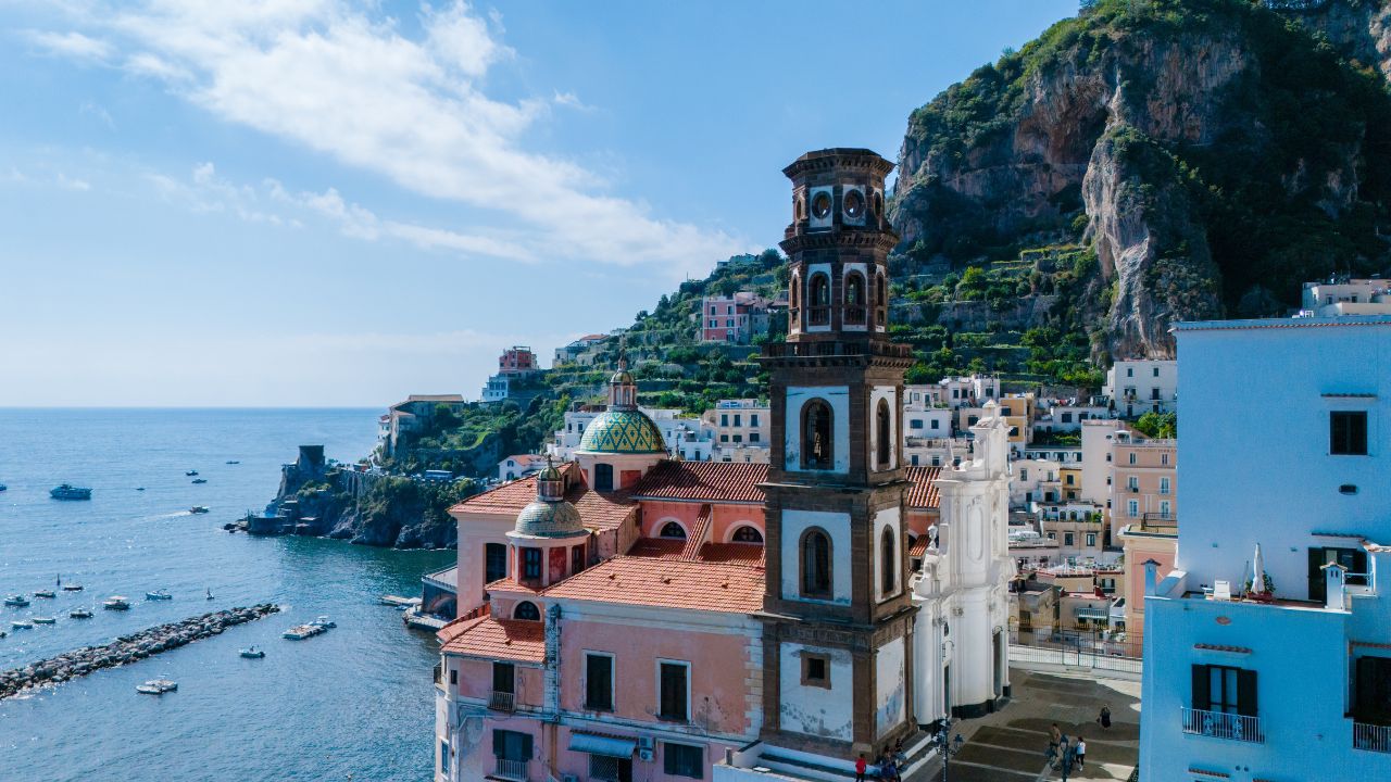 Bask in the beauty of the Amalfi coast as colorful buildings cling to steep cliffs, overlooking tranquil blue waters dotted with boats. Atrani Italy