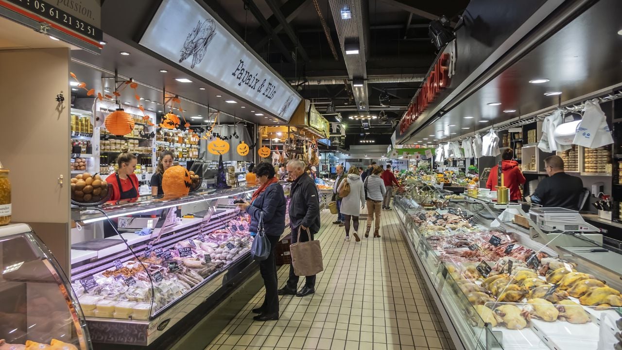 TOULOUSE, FRANCE - OCTOBER 25, 2019: Interior of Marche Victor Hugo - covered market, packed with local producers busily selling cheeses, fresh meats and fish, vegetables, fruit.
