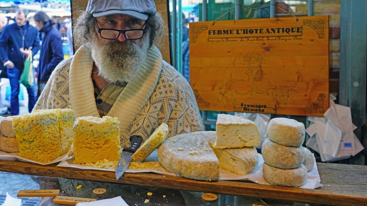 RENNES, FRANCE -28 DEC 2019- View of a man with a big white beard selling cheese at the Marche des Lices farmers market in Rennes, the Brittany capital, France.
