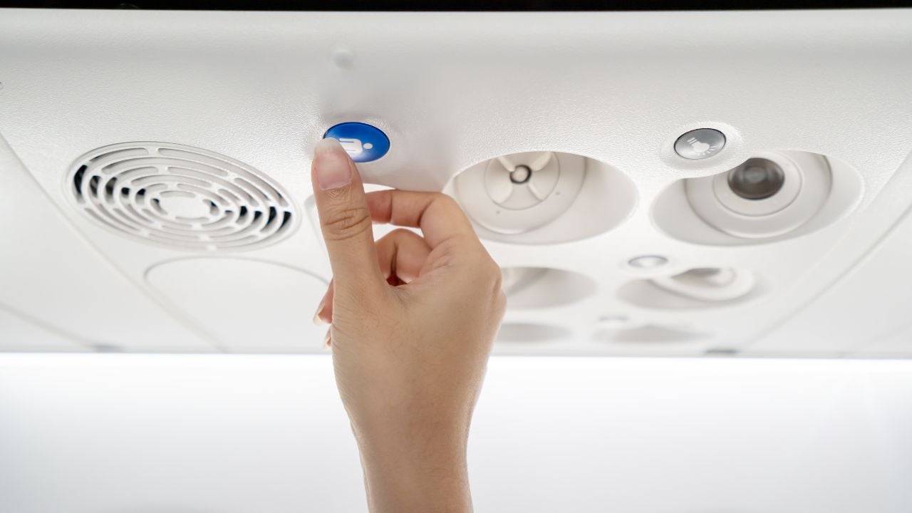 Close up of asian flight attendant's hand call cabin crew or stewardess by pressing help needed button on overhead compartment. Economy class on low cost airline business seated activity concept.