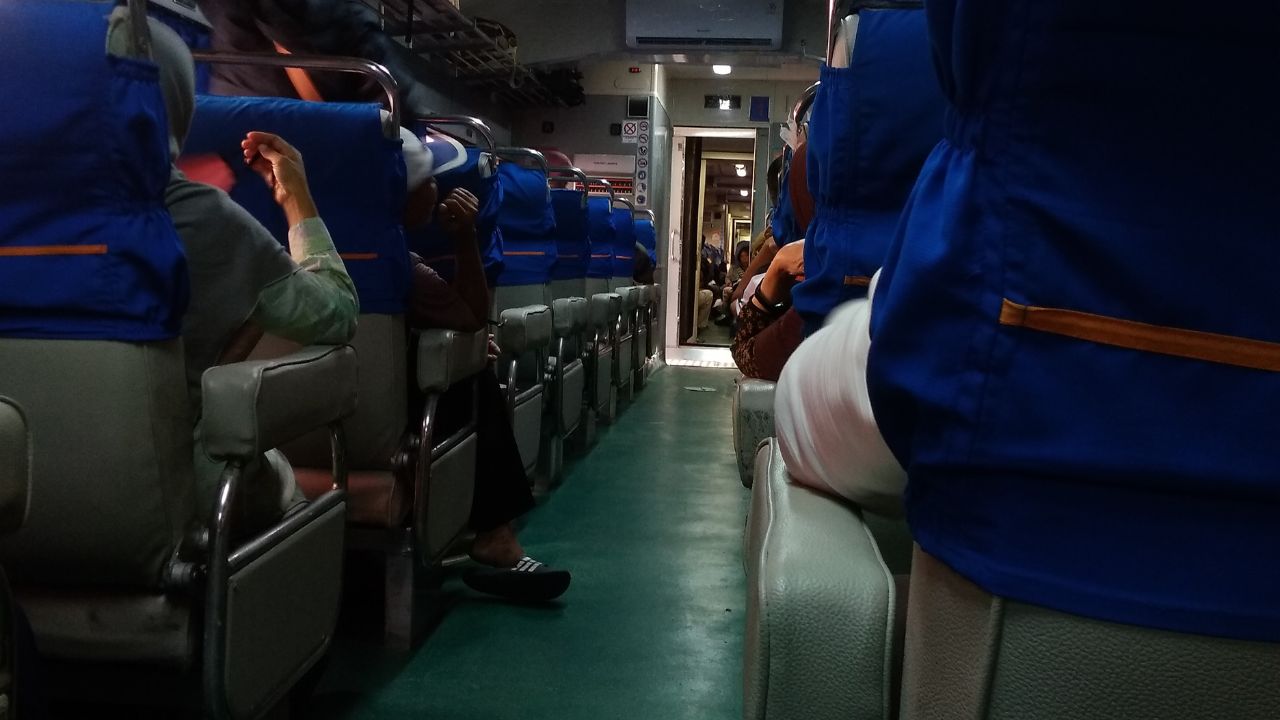 Inside of train with sitting and standing passengers
