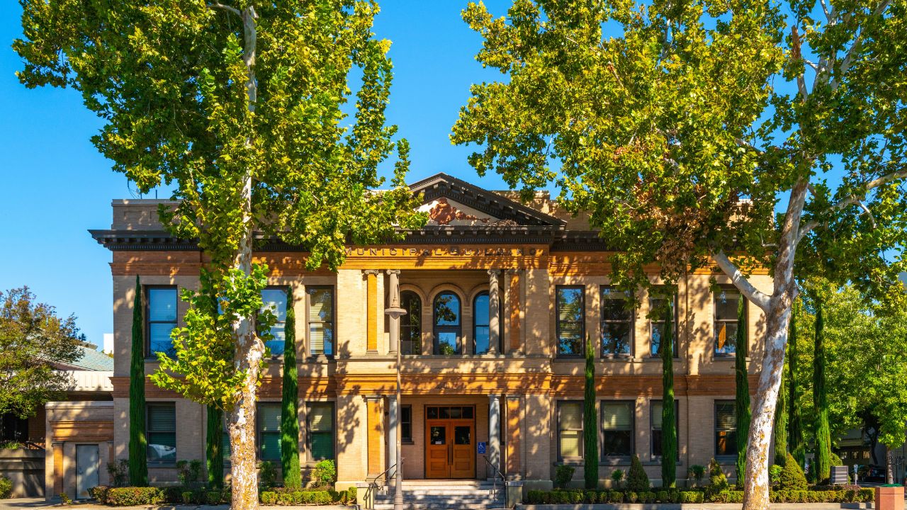 Old Chico City Hall, view from the street, the autumn landscape behind tall sycamore trees, Chico, Northern California