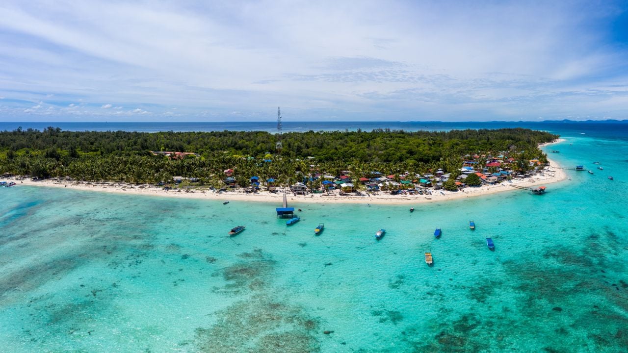 Aerial drone image of beautiful white sandy beach tropical island with turquoise sea water and Malay traditional fisherman village at Mantanani Island, Sabah, Borneo - Travel ConceptAerial drone image of beautiful white sandy beach tropical island with turquoise sea water and Malay traditional fisherman village at Mantanani Island, Sabah, Borneo - Travel Concept