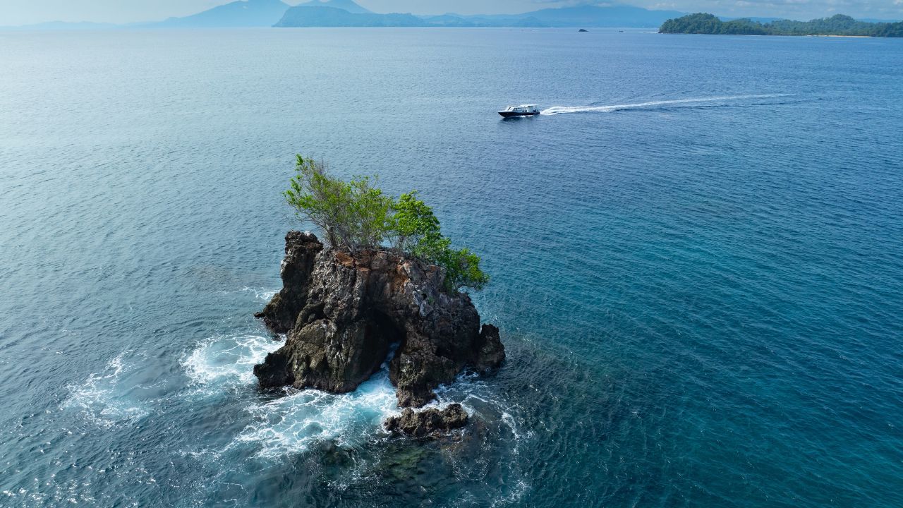 Gentle ocean currents surround a lone rock island found of the coast of Bangka Island, Indonesia. This region is part of the coral triangle and harbors incredible marine biodiversity.