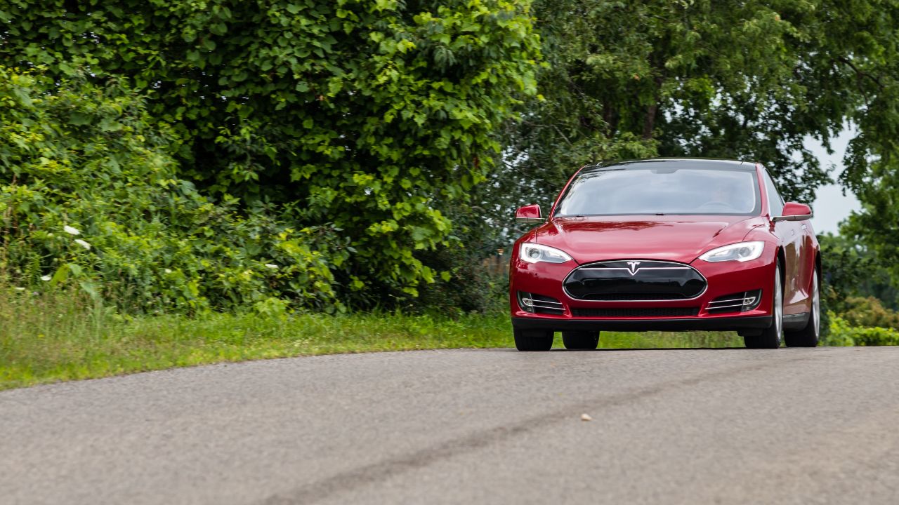 BRANT, CANADA - Red Tesla Model S seen driving down a road.