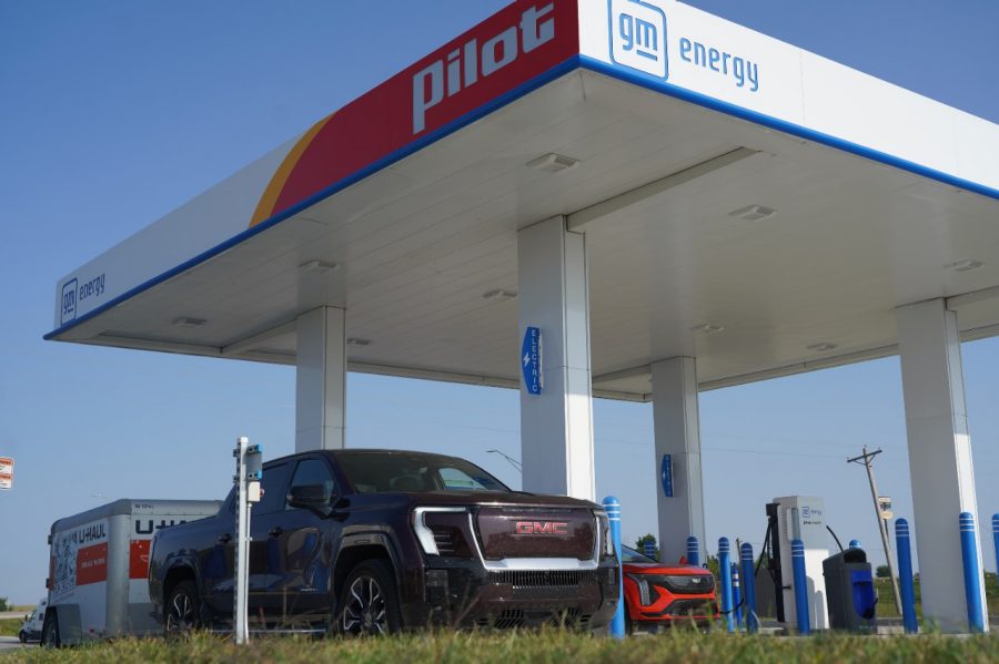 Cadillacs OPTIQ and Sierra EVs at a charging station.