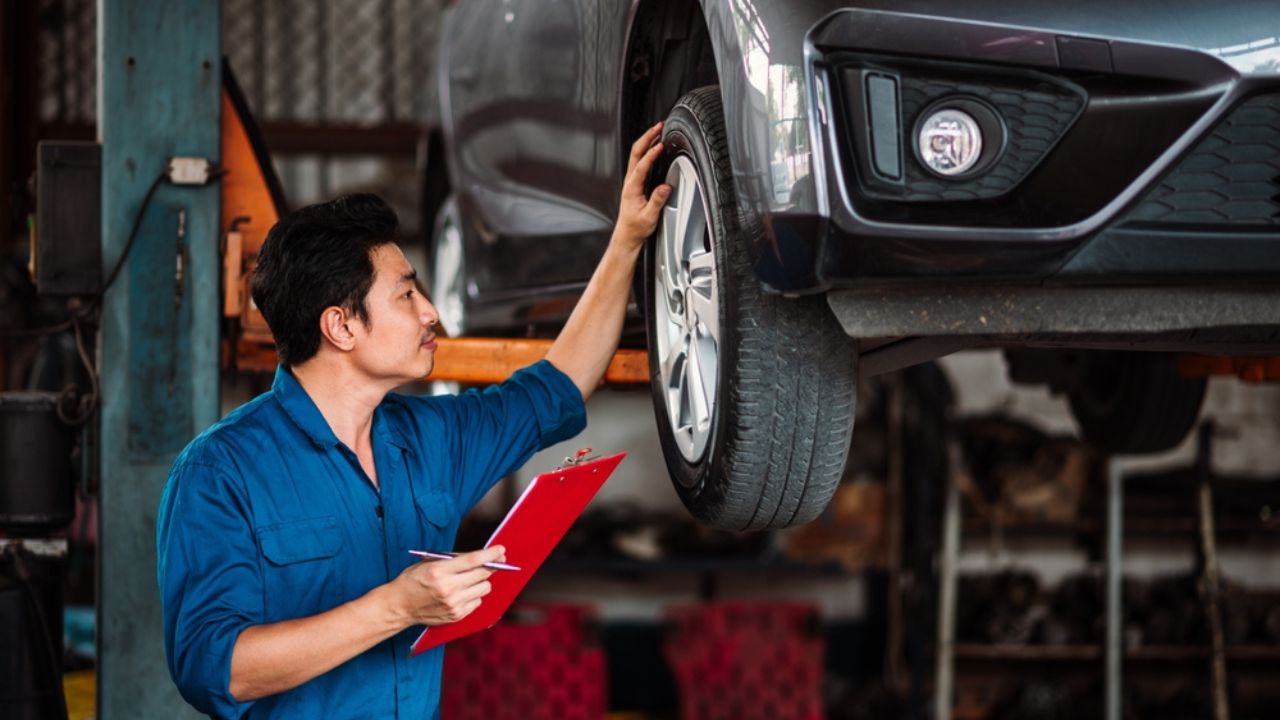 Garage Worker, Automotive Repair , Asian Male Mechanic Wearing Blue Uniform Carefully Inspecting Car Condition According to Checklist in Small Garage