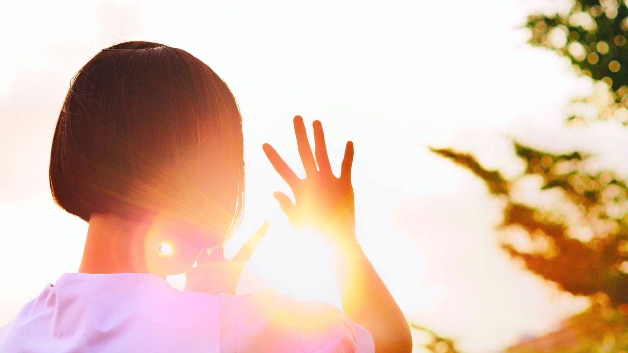 Very hot weather can cause dehydration and Heatstroke. Young women raising hands To block the hot sunlight.