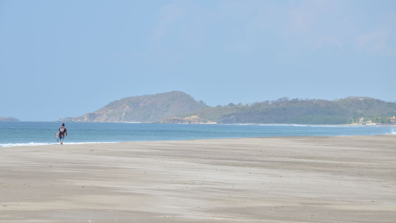 A surfer walks on expansive Popoyo beach on Nicaragua's Pacific coast