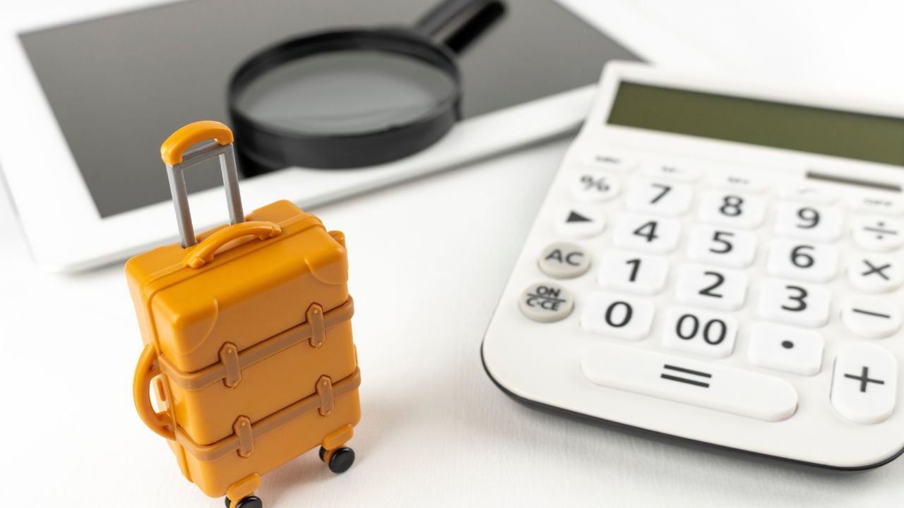 An image of booking a trip on a tablet. A tablet device, a carrying case and a magnifying glass.