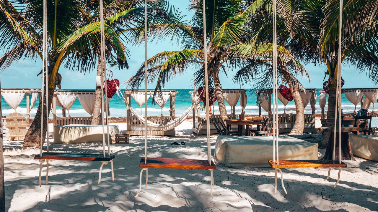 Wooden swing seats on the sand at a beach resort in Tulum, Mexico