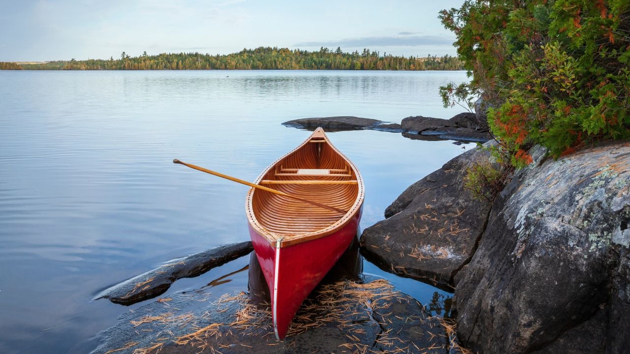 Red wood canoe on rocky shore of a Boundary Waters lake in morning light during autumn