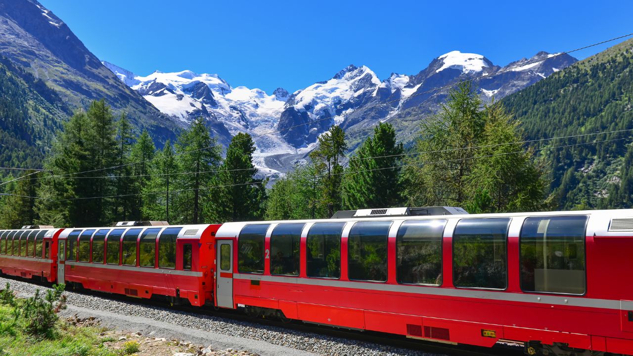 Swiss mountain train Bernina Express crossed Alps with glaciers in the backgroundin the summer