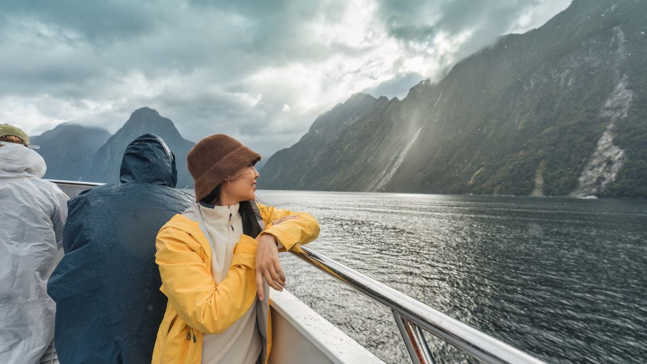 Traveler enjoying the view of Milford Sound during a cruise in Fiordland National Park, New Zealand