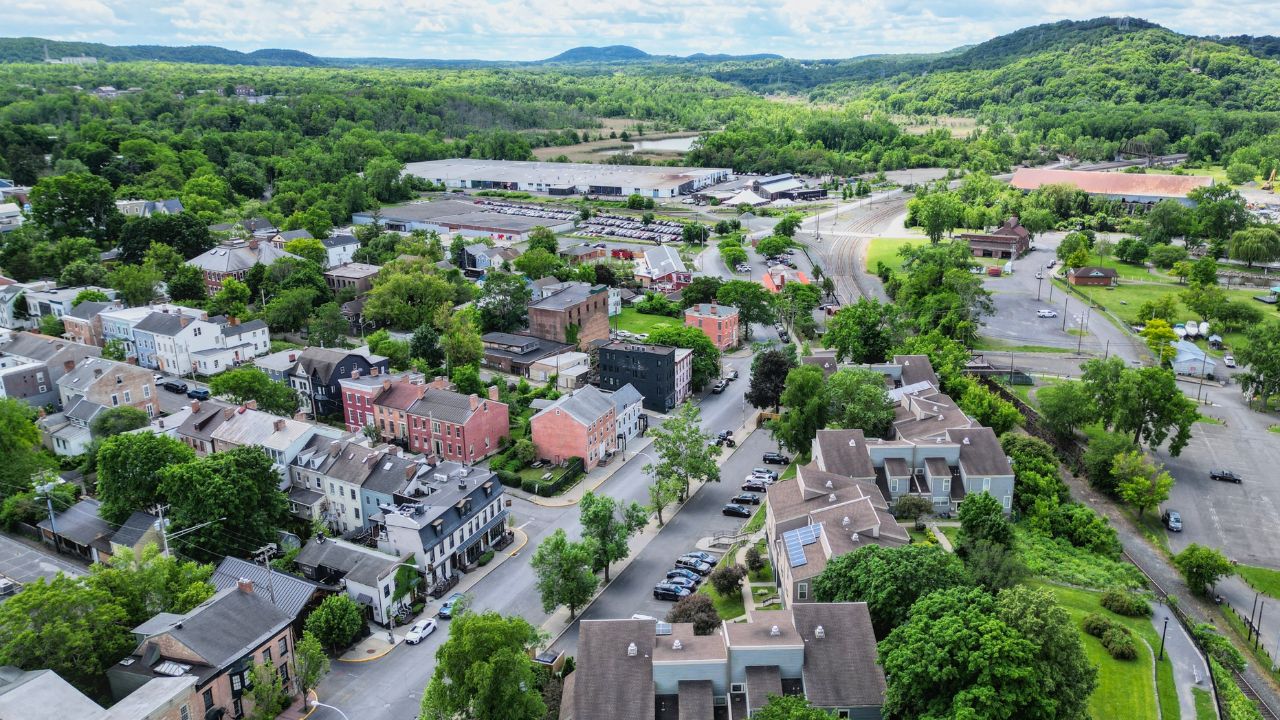 aerial view of hudson, new york (small hudson valley town city downtown historic district) mountains catskills ny travel destination main street with hills clouds cars tree matter