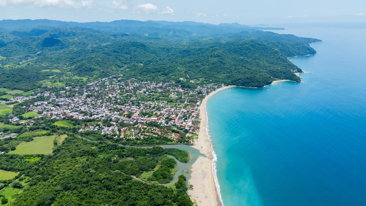 Aerial view of lo de marcos, nayarit, mexico, showcasing the stunning confluence of lush vegetation, sandy beach, and crystal-clear turquoise waters