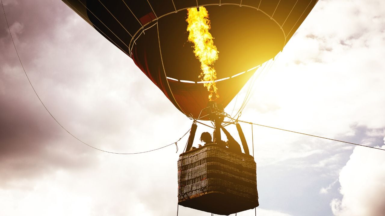 Hot air balloon flying in a cloudy sky at sunrise - Image of balloon silhouette flight over the sky