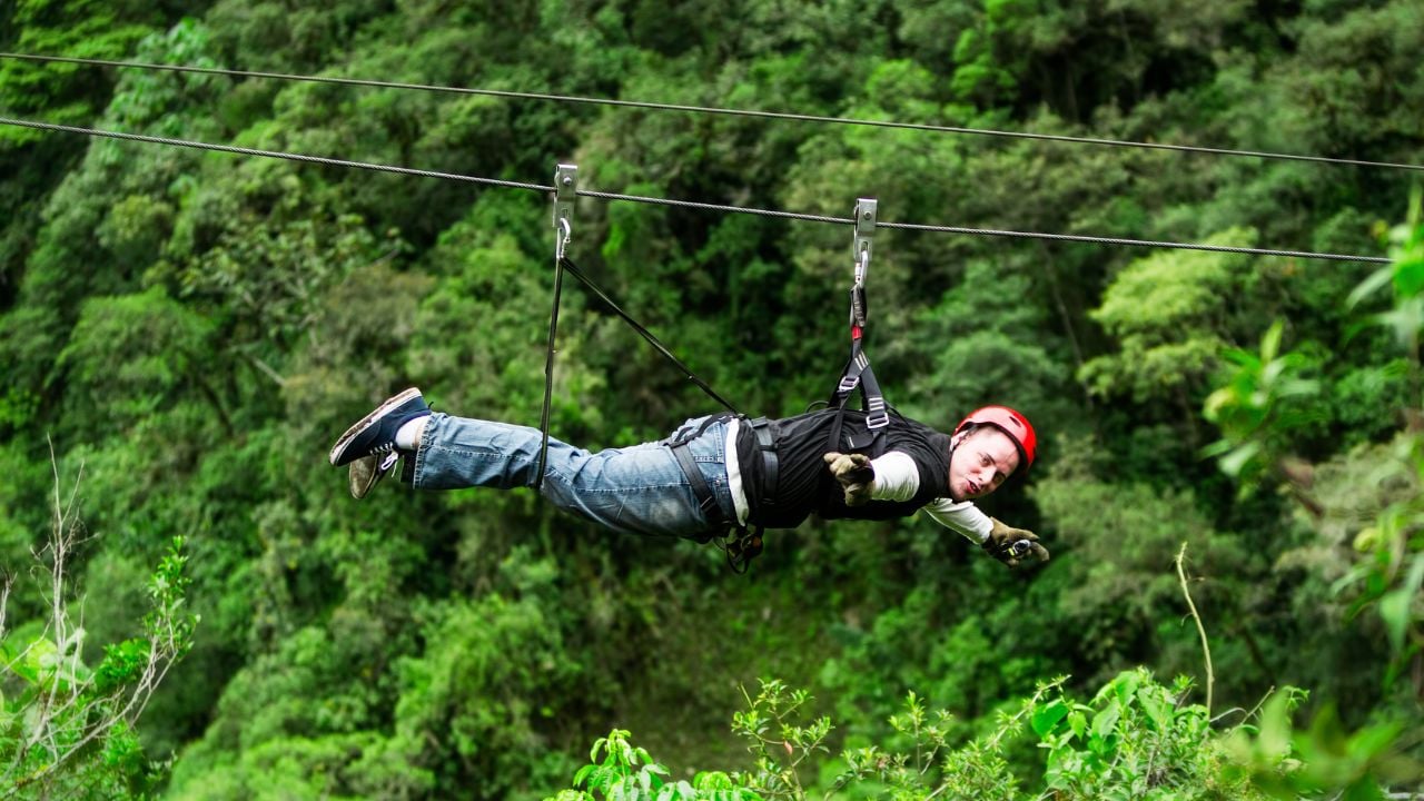 Gliding through the jungle canopy on a zipline, feeling the rush of flight as you zip along a wire with your harness securely in place.