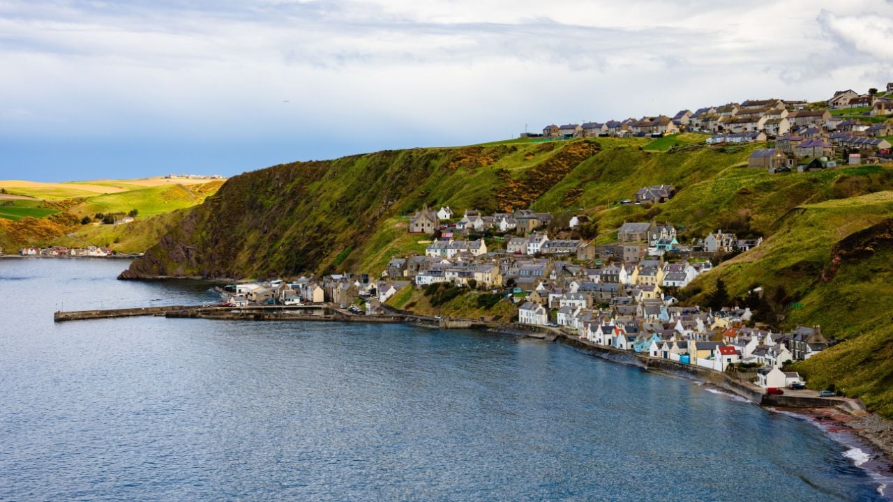 The picturesque village of Gardenstown, Scotland on the northern coast of the UK with blue skies, beautiful blue water and stunning coastal views.