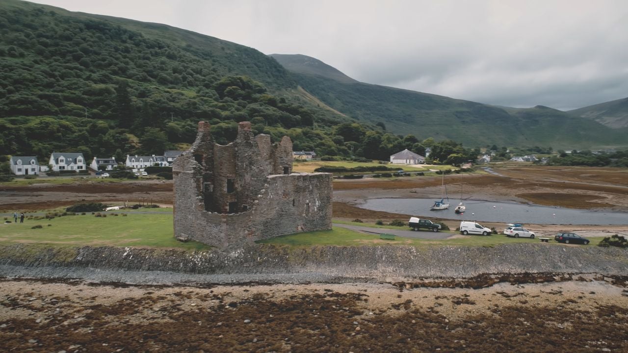 Closeup historical castle ruins aerial. Ruined architecture attraction at sea bay. Historic monument, heritage of culture. Ocean coast of Loch-Ranza, Arran Island, Scotland, United Kingdom, Europe