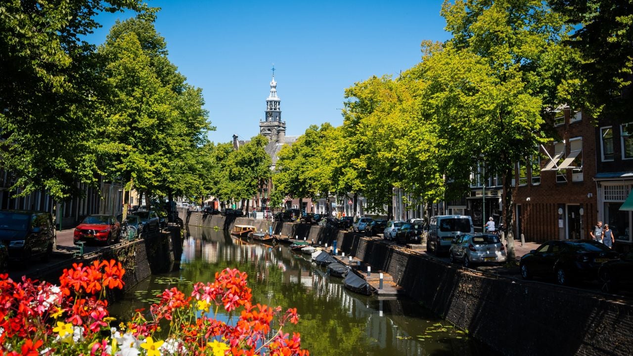 Gouda, Netherlands, August 20th, 2022. A typical Dutch street canal in Gouda in the Netherlands on a sunny summer day. Houses demonstrate local architecture and trees make the street seem more pretty