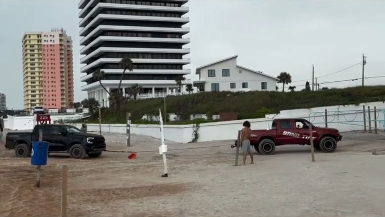 Ford Raptor attempts to tow Ford Explorer stuck in beach sand.
