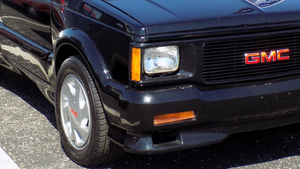 Black 1993 GMC Typhoon Close-up shot of the Headlight, grille, and front wheel