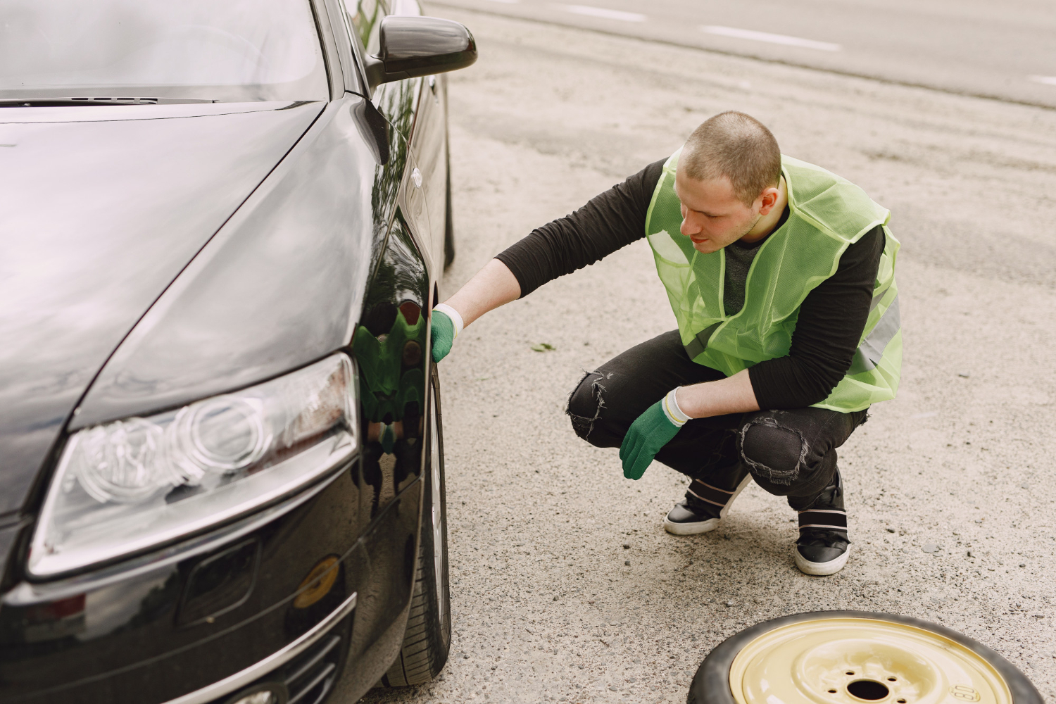 Man changing broken wheel on car.
