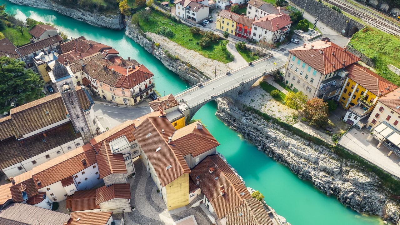 Picturesque aerial view of river Soca in Slovenia - Kanal on the Soca (Kanal ob Soči) village with a beautiful stone arch bridge and old buildings .