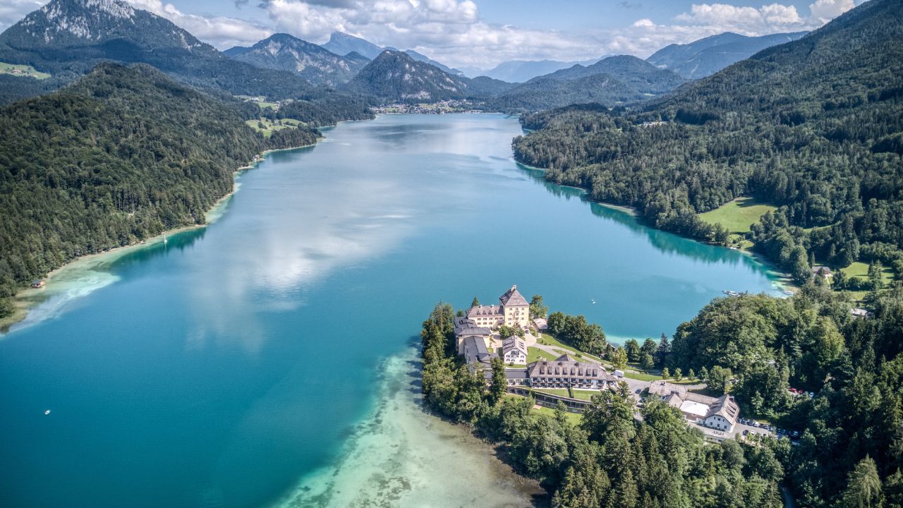 Fuschl, Austria - July 31 2021: Aerial panoramic view over mountain lake Fuschlsee and the Hotel Schloss Fuschl luxury resort, now a Rosewood Hotel
