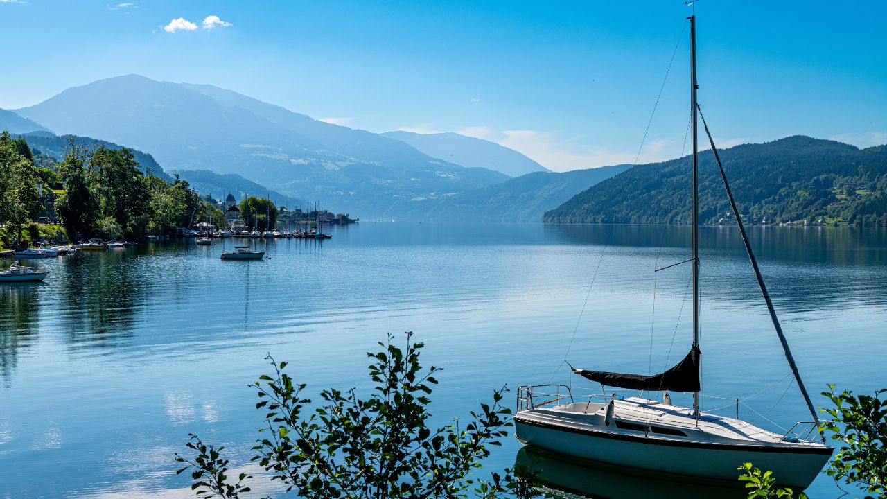 Millstatt am See, Kärnten - Austria - 06-16-2021: Millstätter Lake: An anchored sailboat floats on a tranquil Austrian lake, framed by alpine mountains
