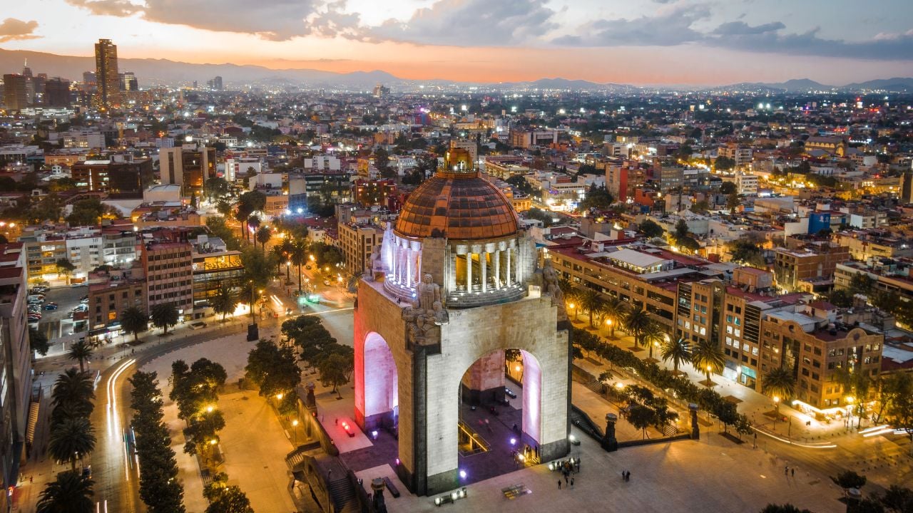 Aerial view of city centre showing architectural landmark Monument to the Revolution (Spanish: Monumento a la Revolucion) located in Plaza de la Republica at dusk in Mexico City, Mexico.