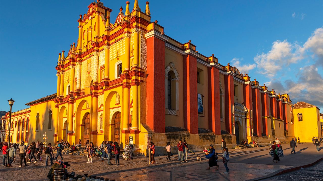 SAN CRISTOBAL DE LAS CASAS, MEXICO - APRIL 2, 2020: Mexican city life with street vendors and people by the Cathedral facade at sunset.