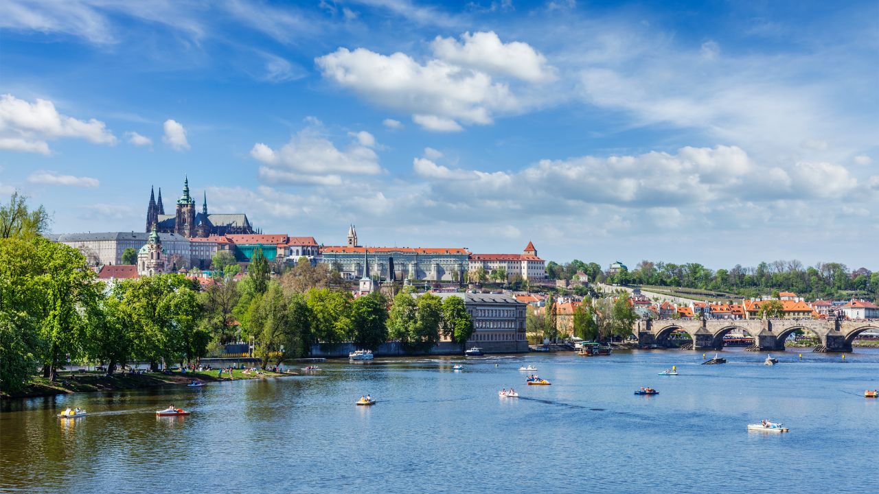 Panorama view of Vltava river and Gradchany (Prague Castle) and St. Vitus Cathedral and Charles bridge an people in paddle boats in the Prague, Czech Republic