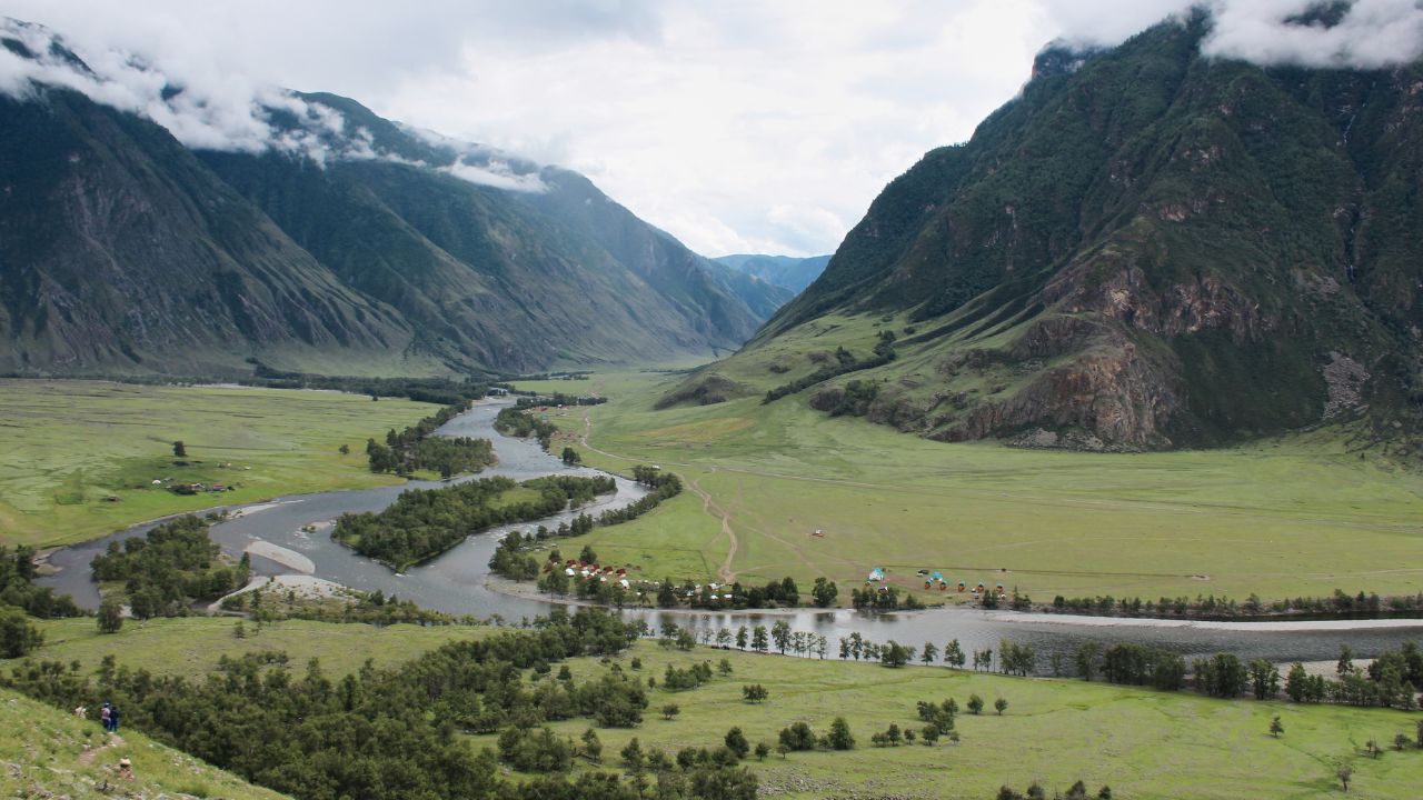 Picturesque green River Valley. Summertime natural landscape, mountains in the clouds, best recreation areas with amazing view. Altai Republic, Siberia, Russia.