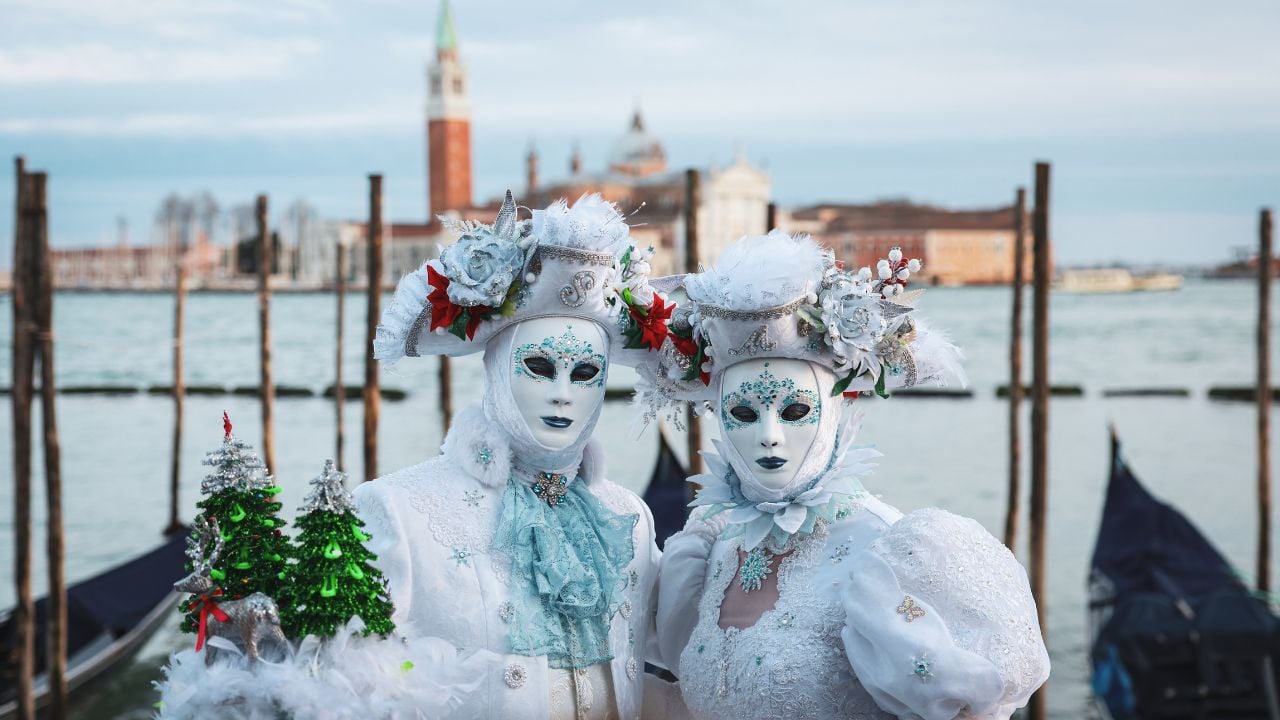 Venice, Italy - March 01, 2025: Venice Carnival participants in elegant costumes by the water during daytime