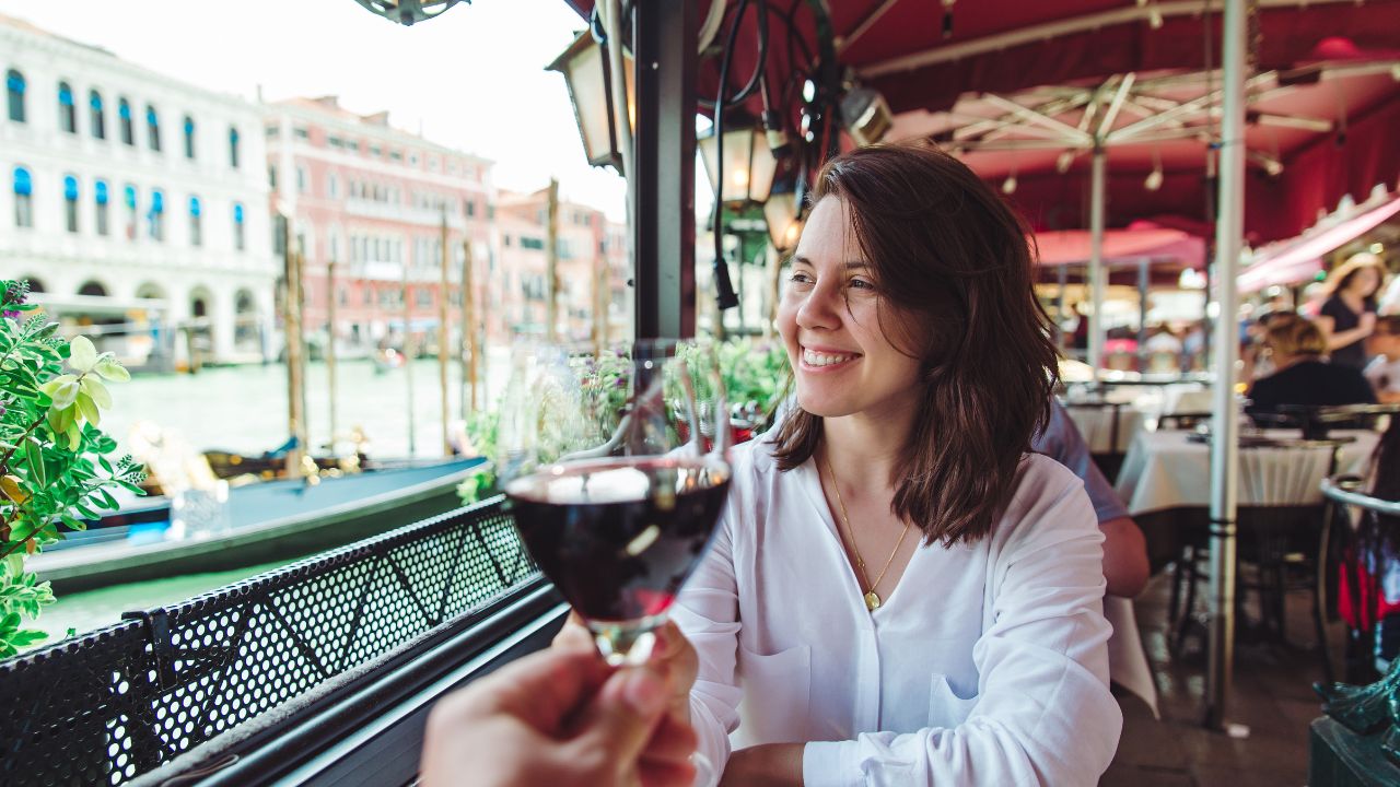 first person point of view couple in cafe outdoors drinking wine smiling woman grand canal venice