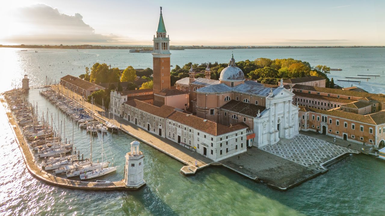 Aerial view of San Giorgio Maggiore island and Grand Canal in Venice, Italy, at sunrise. Stunning landscape of the Venetian lagoon with historic architecture and calm morning atmosphere.