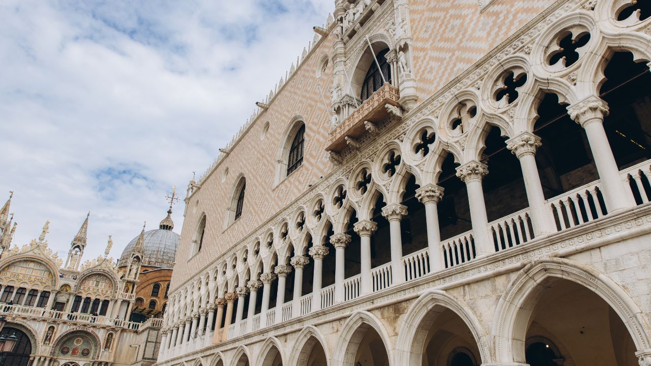 Historic architecture of Doge's Palace in Venice, Italy with intricate Gothic details and famous St Mark's Basilica domes