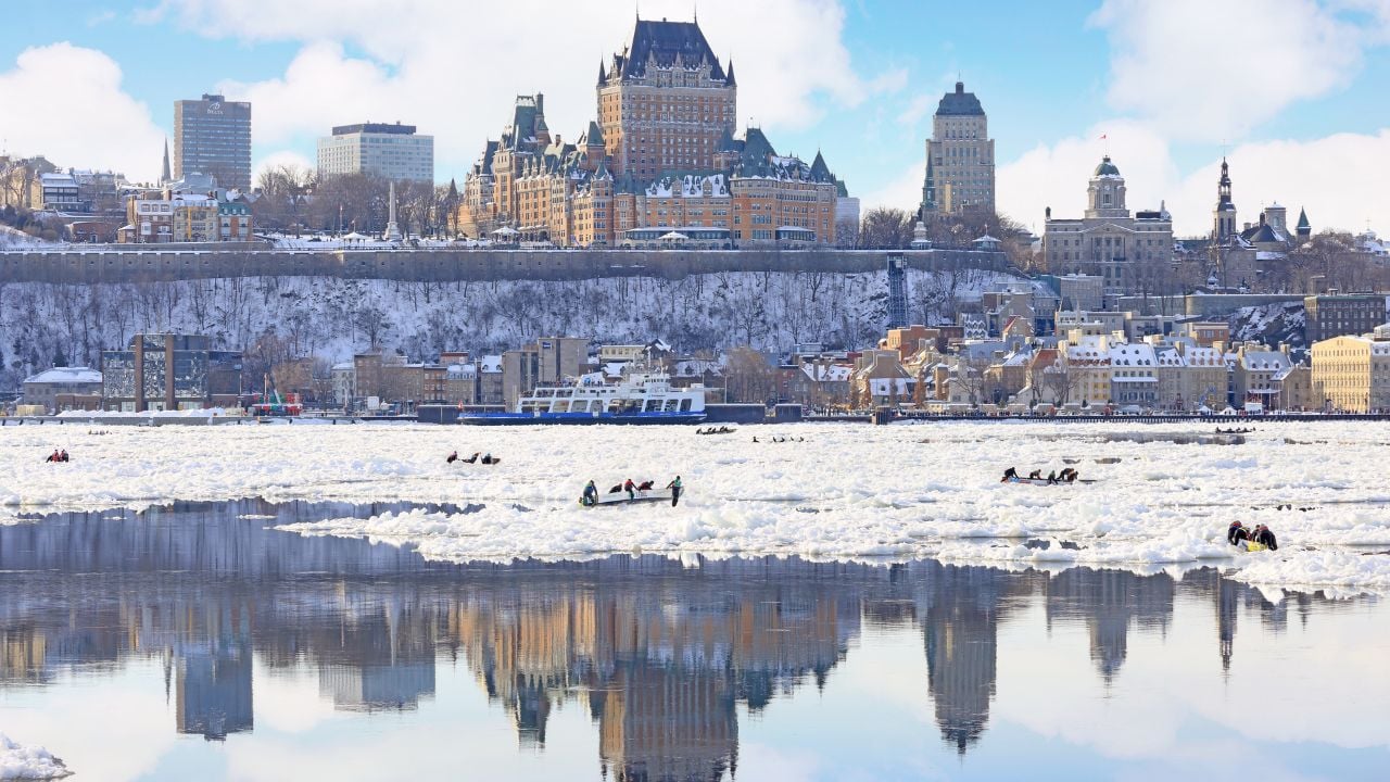 Quebec City, Canada - February 9, 2025: Traditional Ice Canoe Race from Quebec to Levis during winter Carnival with city skyline reflected on the frozen Saint Lawrence River