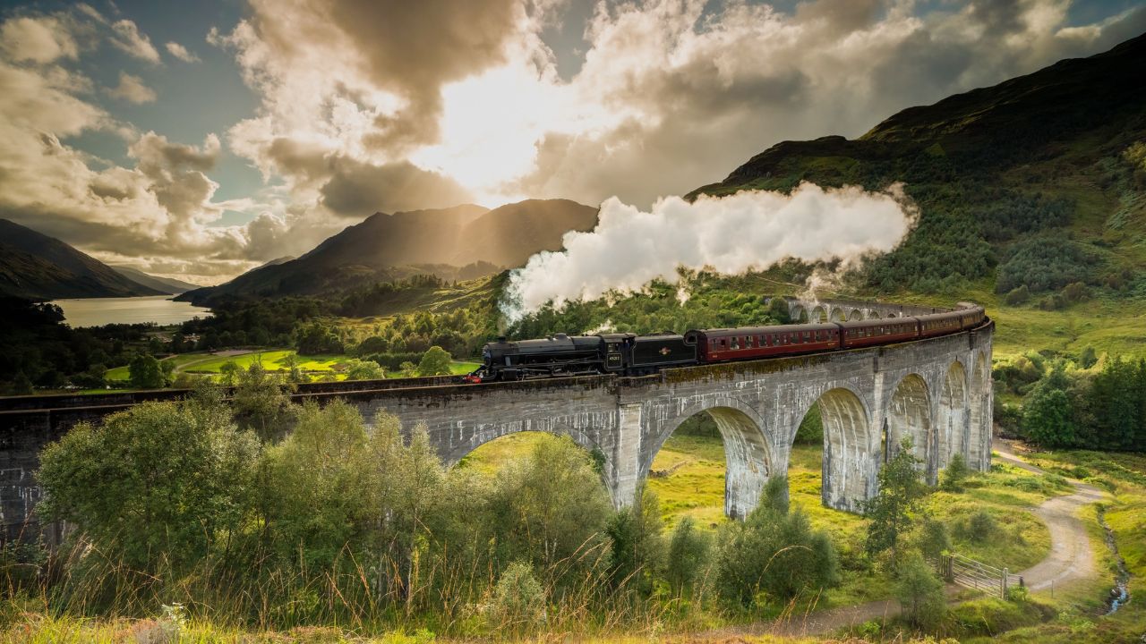 Jacobite steam train crossing the Glenfinnan Viaduct with steam rising from the chimney. Hogwarts Express, Harry Potter.